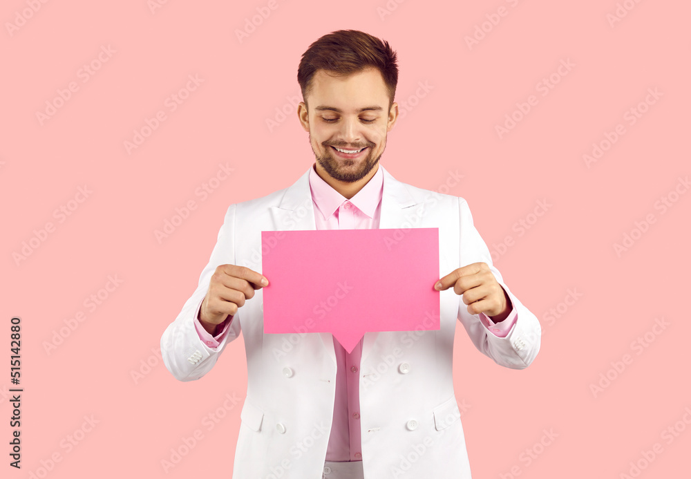 Studio shot of nice smiling gentleman with blank clean rectangular paper speech balloon. Happy handsome young man in suit holding empty mockup pink messenger or social media chat message bubble Studio shot of nice smiling gentleman with blank clean rectangular paper speech balloon. Happy handsome young man in suit holding empty mockup pink messenger or social media chat message bubble