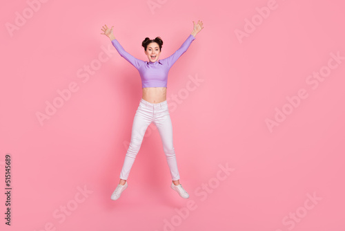 Full size photo of cheerful satisfied person jumping raise hands isolated on pink color background