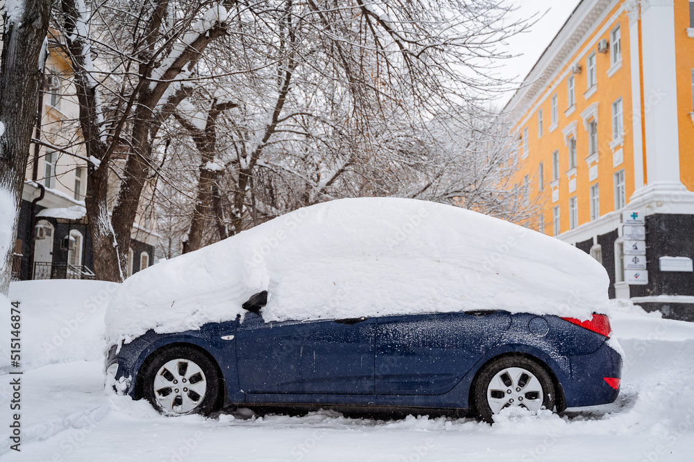 The car is buried under a layer of snow. Heavy snowfall in the city. The equipment stands under a snowdrift. Consequences of a winter hurricane.