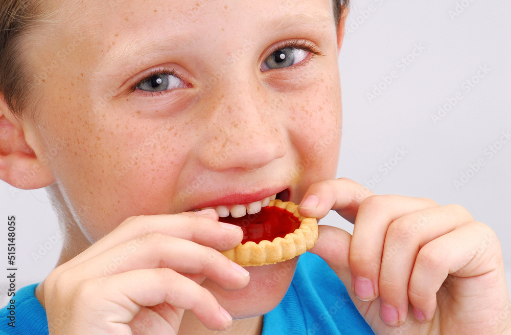 Happy kid eating strawberry cookie on white. Happy kid eating strawberry cookie on white.