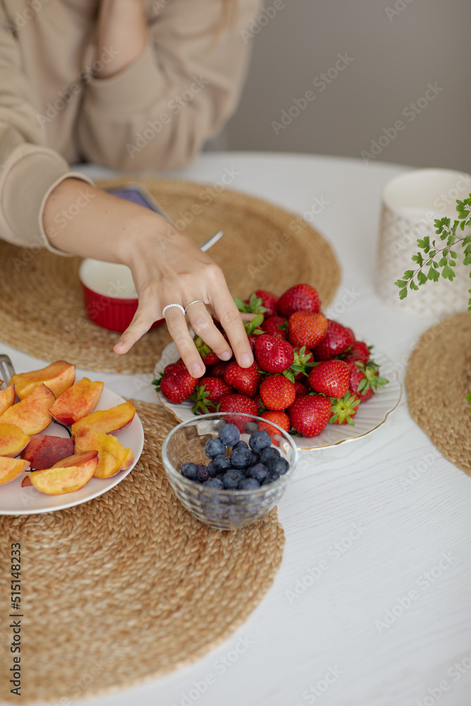 The girl holds a krubnik in her hand and is going to eat it. A healthy fruit breakfast. Abundance of summer berries. Kubnik and blueberry