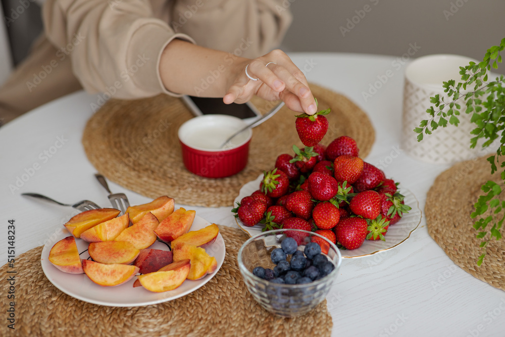 The girl holds a krubnik in her hand and is going to eat it. A healthy fruit breakfast. Abundance of summer berries. Kubnik and blueberry