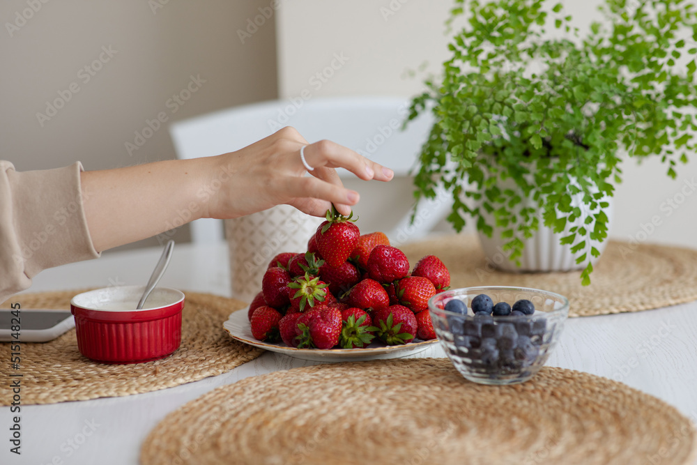 The girl holds a krubnik in her hand and is going to eat it. A healthy fruit breakfast. Abundance of summer berries. Kubnik and blueberry