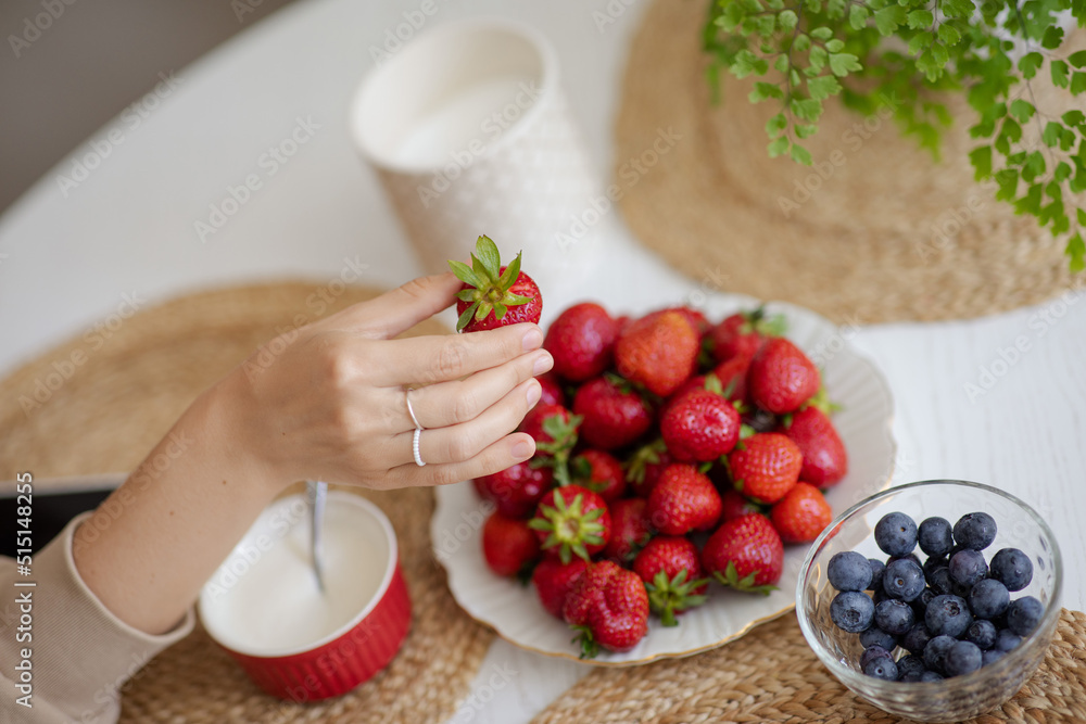 The girl holds a krubnik in her hand and is going to eat it. A healthy fruit breakfast. Abundance of summer berries. Kubnik and blueberry
