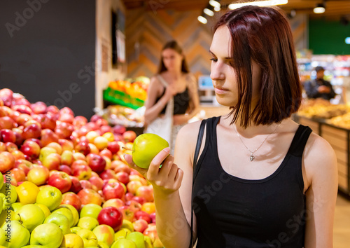 Woman in a supermarket at the shelf for fruits shopping apple