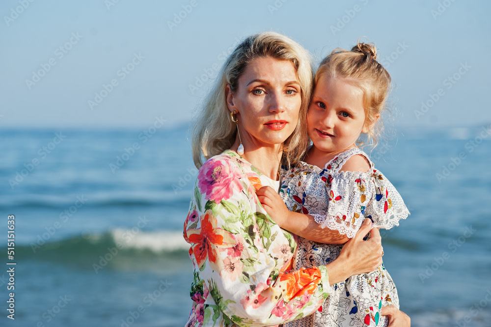 Mother and beautiful daughter having fun on the beach. Portrait of happy woman with cute little girl on vacation.