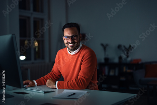 Portrait of a smiling man, staying at the office late at night.