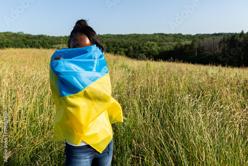 African american woman wrapped in ukrainian yellow blue flag flutters waving in the wind. National symbol of Ukraine. Stand with Ukraine, international support and solidarity 