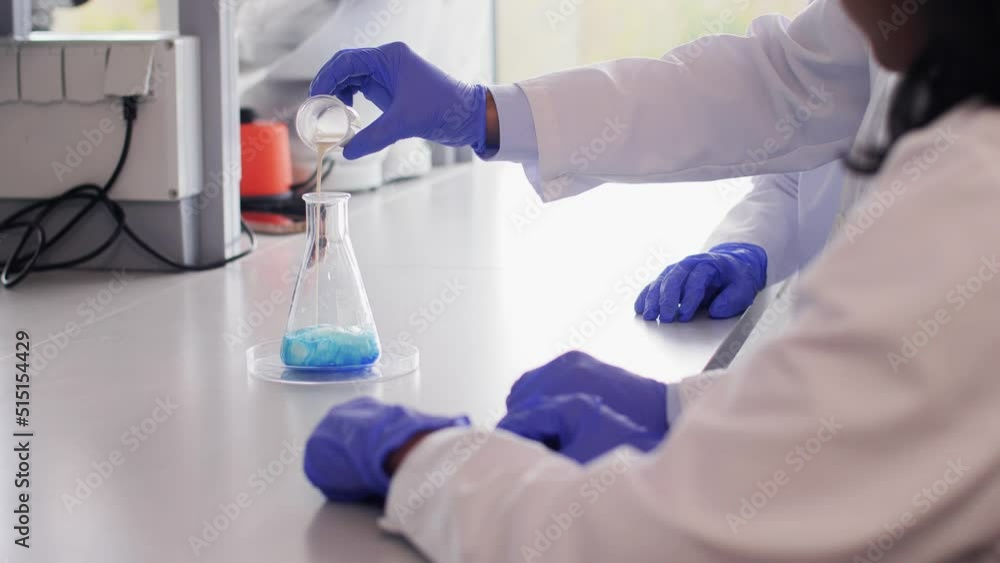 science research, work and people concept - international team of scientists with chemicals working in laboratory science research, work and people concept - international team of scientists with chemicals working in laboratory