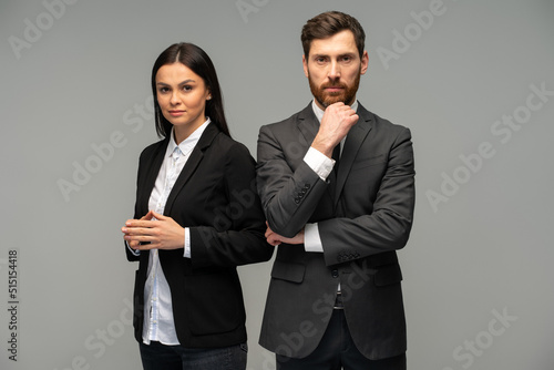 Confident happy young business partners looking at camera while posing isolated on grey background. Business concept