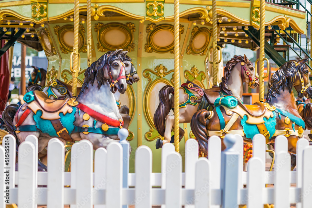 Children's carousel with horses in retro style. A fragment of a multi-colored vintage carousel in the park. Close-up.