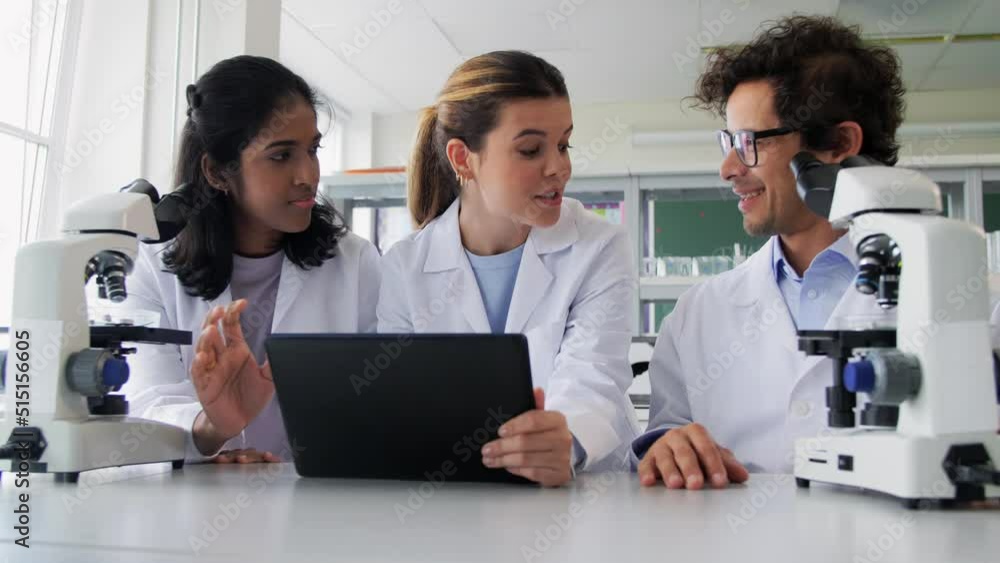 science research, work and people concept - international team of scientists with microscopes and tablet pc computer working in laboratory science research, work and people concept - international team of scientists with microscopes and tablet pc computer working in laboratory