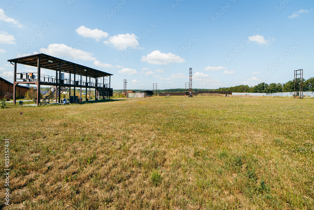 Empty shotgun training field with green grass and plat machines Empty shotgun training field with green grass and plat machines