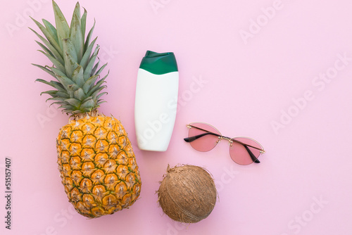 Pineapple and coconut and sunglasses on a bright pink background. Hello summer concept