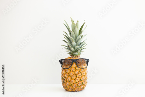 Ripe pineapple in sunglasses on a white background. Summer vacation. Hello summer