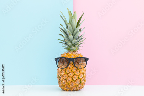 Fresh pineapple with sunglasses on color background