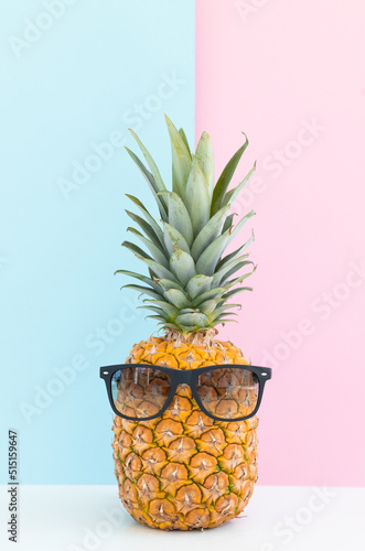 Fresh pineapple with sunglasses on color background