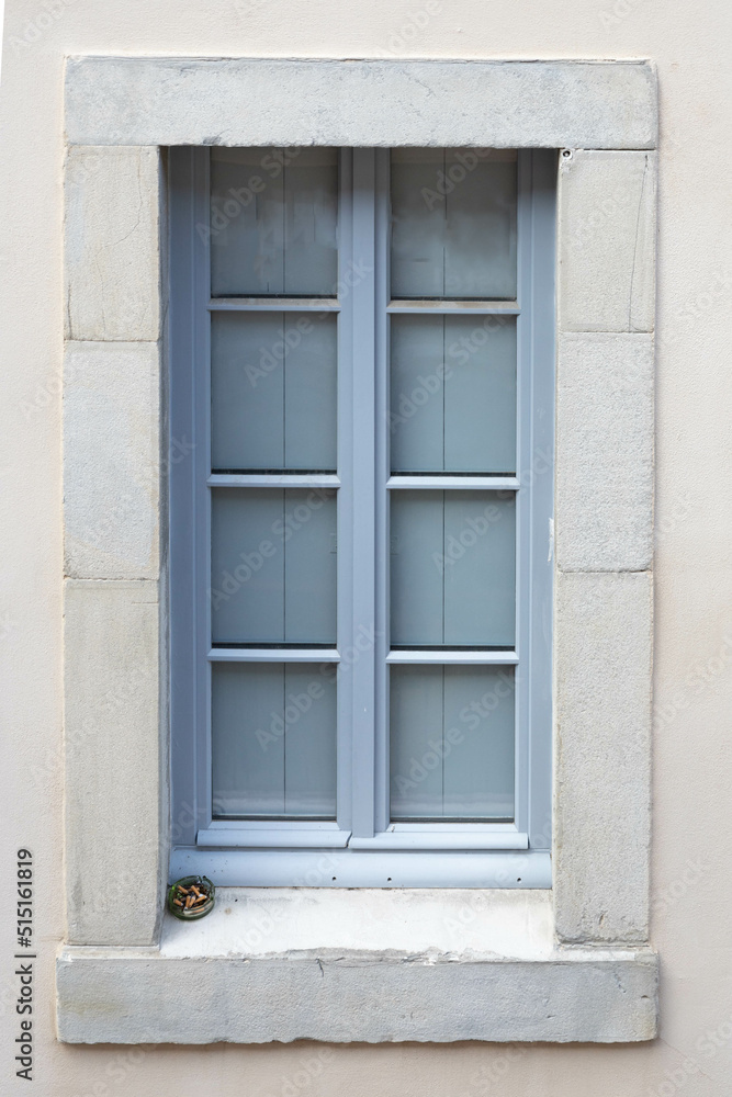 French blue window with an ashtray full of stubs in a stone wall