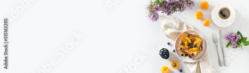 Trendy breakfast offer banner. Stack of delicious french toasts with berries, a cup of coffee and lilac flowers bouquet on white background. Copy space. Restaurant, backery web line. Top view photo