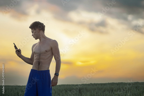 sporty man in shorts in nature on a run uses a mobile application for training.