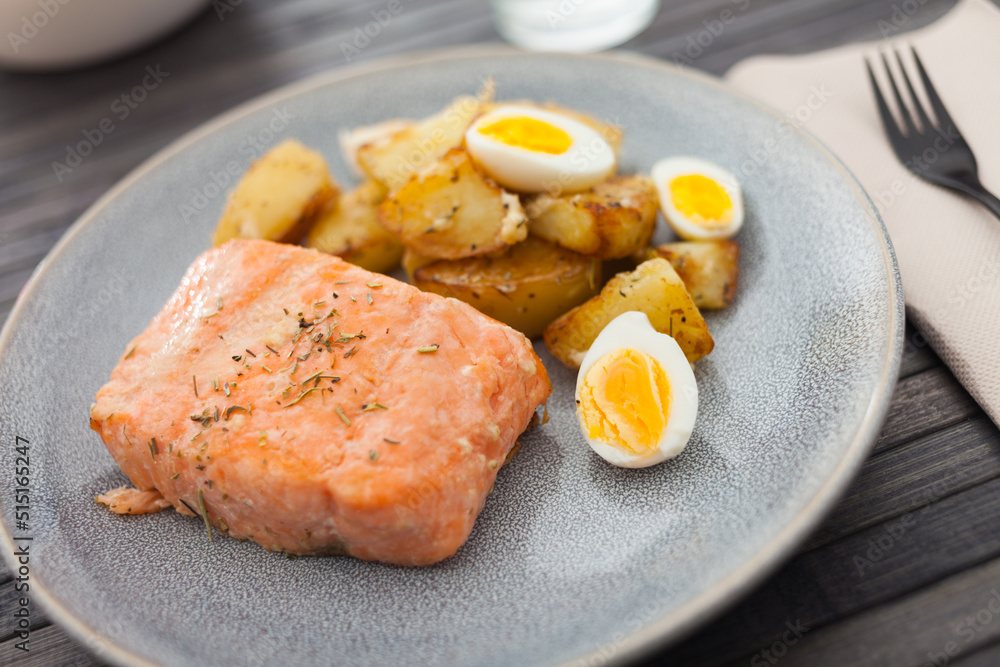baked salmon fillet with fried potato wedges and quail eggs halves