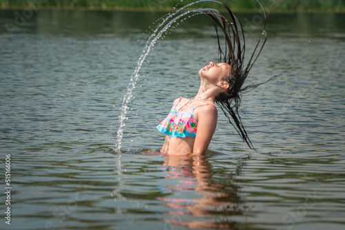Fototapeta Naklejka Na Ścianę i Meble -  A little girl splashes in a pond during the day.