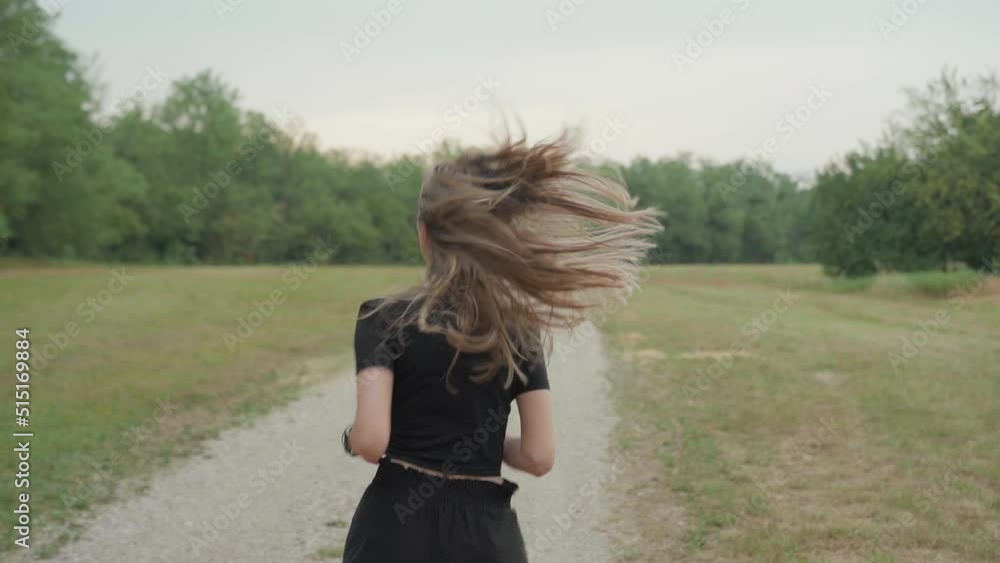 Fit woman wit long beautiful blonde hair model running in natural park. Young woman in sport clothes exercising outdoor, shot from behind of long hair moving on shoulders. Spring summer activities Fit woman wit long beautiful blonde hair model running in natural park. Young woman in sport clothes exercising outdoor, shot from behind of long hair moving on shoulders. Spring summer activities