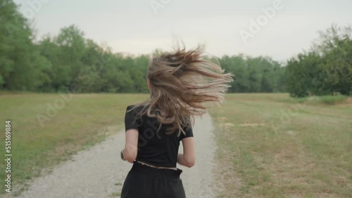 Fit woman wit long beautiful blonde hair model running in natural park. Young woman in sport clothes exercising outdoor, shot from behind of long hair moving on shoulders. Spring summer activities