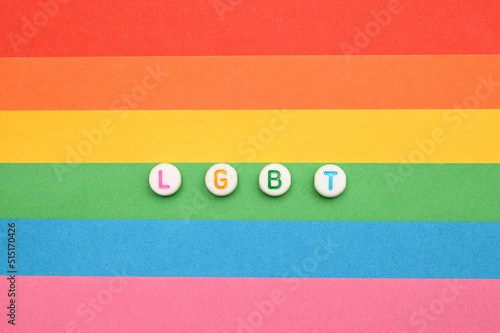 The inscription LGBT made of beads on a rainbow background.
