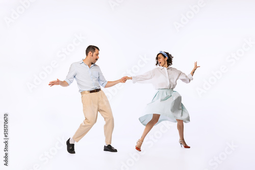 Portrait of young beautiful couple, man and woman, dancing swing isolated over white studio background