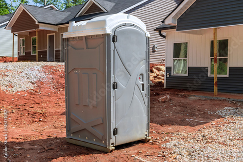 The portable restroom on the construction site of a house under construction is being used by workers photo