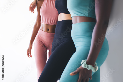 Cropped view of multiracial female athletes in stylish sportswear keeping healthy lifestyle and body positive concept, group of young unrecognizable fit girls in tracksuits slimming togetherness