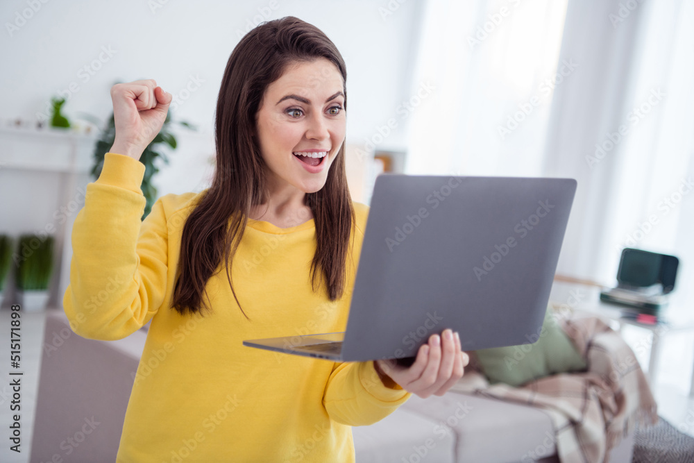 Photo of delighted person use netbook raise fist celebrate achievement luck house indoors Photo of delighted person use netbook raise fist celebrate achievement luck house indoors