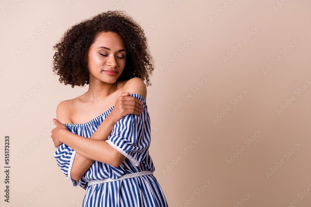 Photo of shiny adorable lady wear striped outfit embracing herself empty space isolated beige color background Photo of shiny adorable lady wear striped outfit embracing herself empty space isolated beige color background