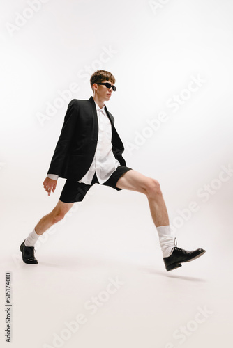 One young stylish man  student in black shorts and jacket posing isolated over white background. Concept of fashion  youth  emotions  studying  ad
