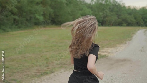 Fit woman running in natural park with long beautiful blonde hair. Young woman in sport clothes exercising outdoor, shot from behind with long hair moving on shoulders. Spring summer activities 