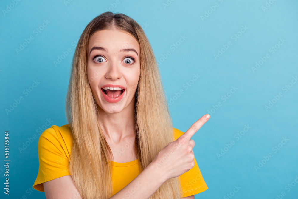 Photo of excited sweet young woman dressed shirt smiling pointing finger empty space isolated blue color background Photo of excited sweet young woman dressed shirt smiling pointing finger empty space isolated blue color background