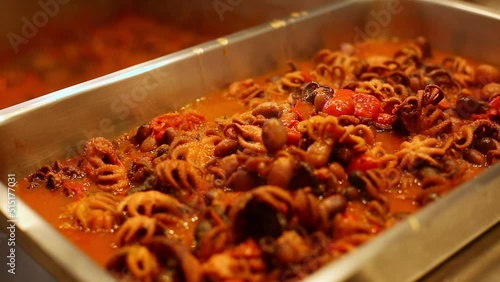 Octopuses with tomato .Typical Italian recipe ,Guazzetto, octopus Luciana ,moscardini in umido.Chef, fills the container with stewed octopus the kitchen in the hotel, restaurant, self service photo