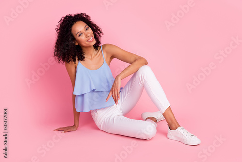 Full size photo of cheerful adorable young girl sitting floor toothy smile isolated on pink color background