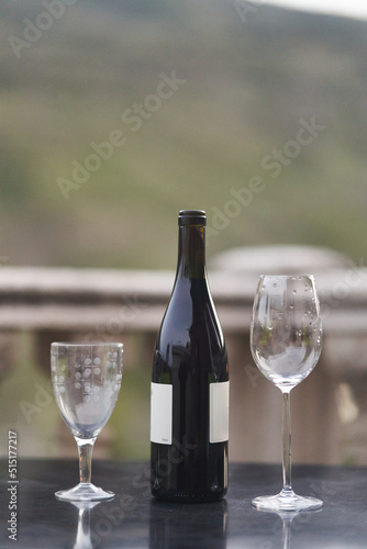 A bottle of wine and two glasses on the table at the balcony of the restaurant. High quality photo