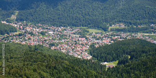 Aerial panorama of Busteni village in Prahova Valley, surrounded by forest, a popular outdoor destination in Romania.