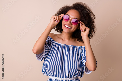 Photo of pretty dreamy lady wear striped outfit arm dark glasses smiling empty space isolated beige color background