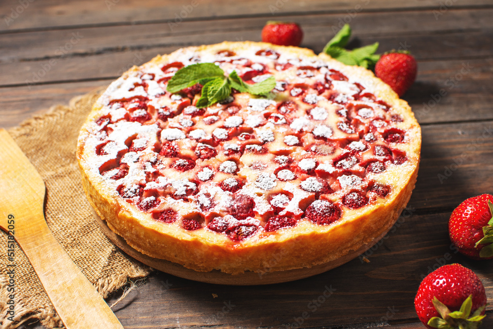 Homemade strawberry custard tart decorated with strawberry on wooden background