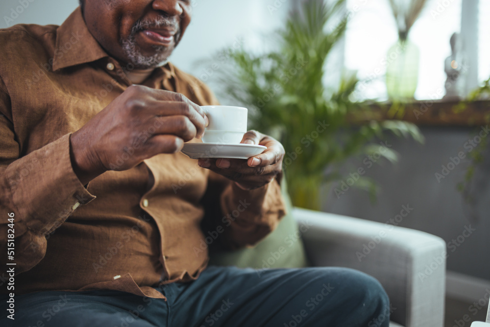 Cropped shot of a contemplative senior man seating alone in his home and enjoying a cup of coffee. Senior Black Man Enjoying a Cup of Coffee at Home Cropped shot of a contemplative senior man seating alone in his home and enjoying a cup of coffee. Senior Black Man Enjoying a Cup of Coffee at Home
