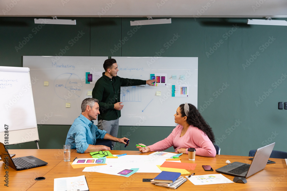 Businessman explaining business strategy to multiracial colleagues in meeting at creative office Businessman explaining business strategy to multiracial colleagues in meeting at creative office