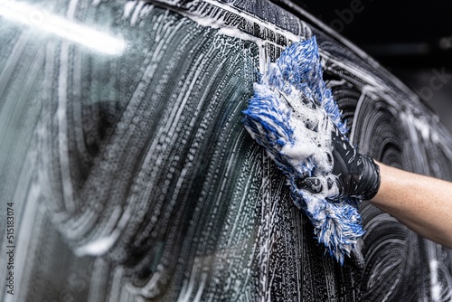 car wash employee thoroughly washes a modern car with a dedicated washing mitt photo