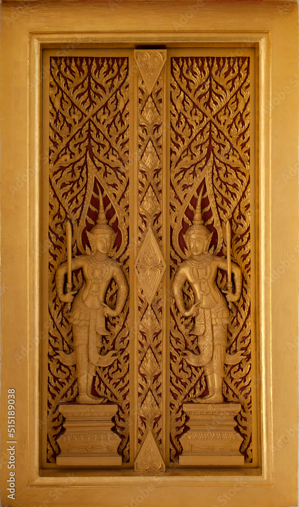 The golden wooden temple door is carved with two deities and exquisite ancient Thai patterns. Decorations at the entrance to the church