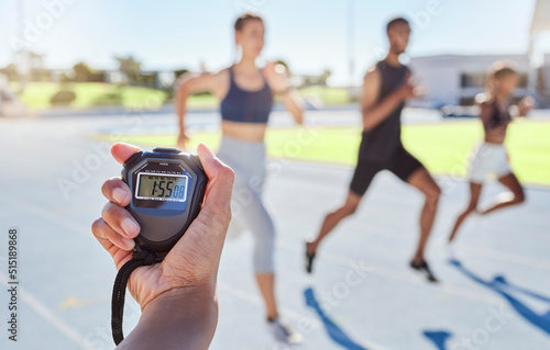 Fototapeta Naklejka Na Ścianę i Meble -  A sport coach timing athletes progress using a stopwatch. .Blurred athletes racing towards finish line and breaking the record. Stopwatch measuring time for a marathon at a sports event.