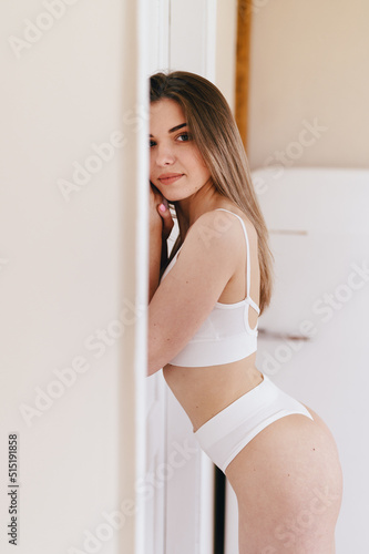 Vertical portrait of Young Woman in White Underwear leans against wall