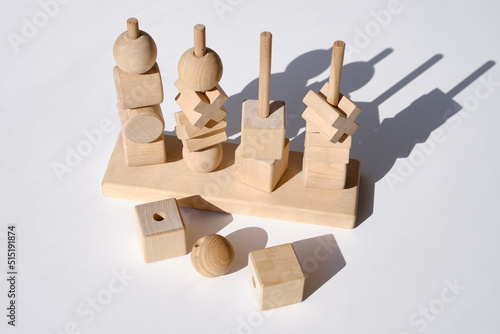 Wooden children's toy puzzle on a light background in the sun. Wooden building blocks for kids isolated on white background. Logical thinking. Puzzle
